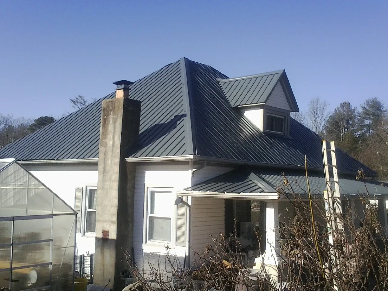 Dark blue standing seam metal roof on a white farmhouse with dormer — Slate & Tile Roof Repair by Roofing Brothers in Oak Forest