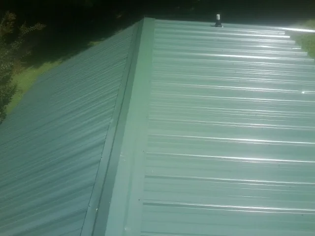 New green metal panels meeting at the ridge of a roof — Flat Roof Repair work by our crew in Oak Forest