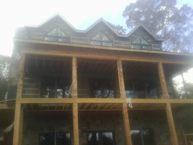 Dormers and porch framing on a large log home under construction — Roof Coating work by our crew in Oak Forest