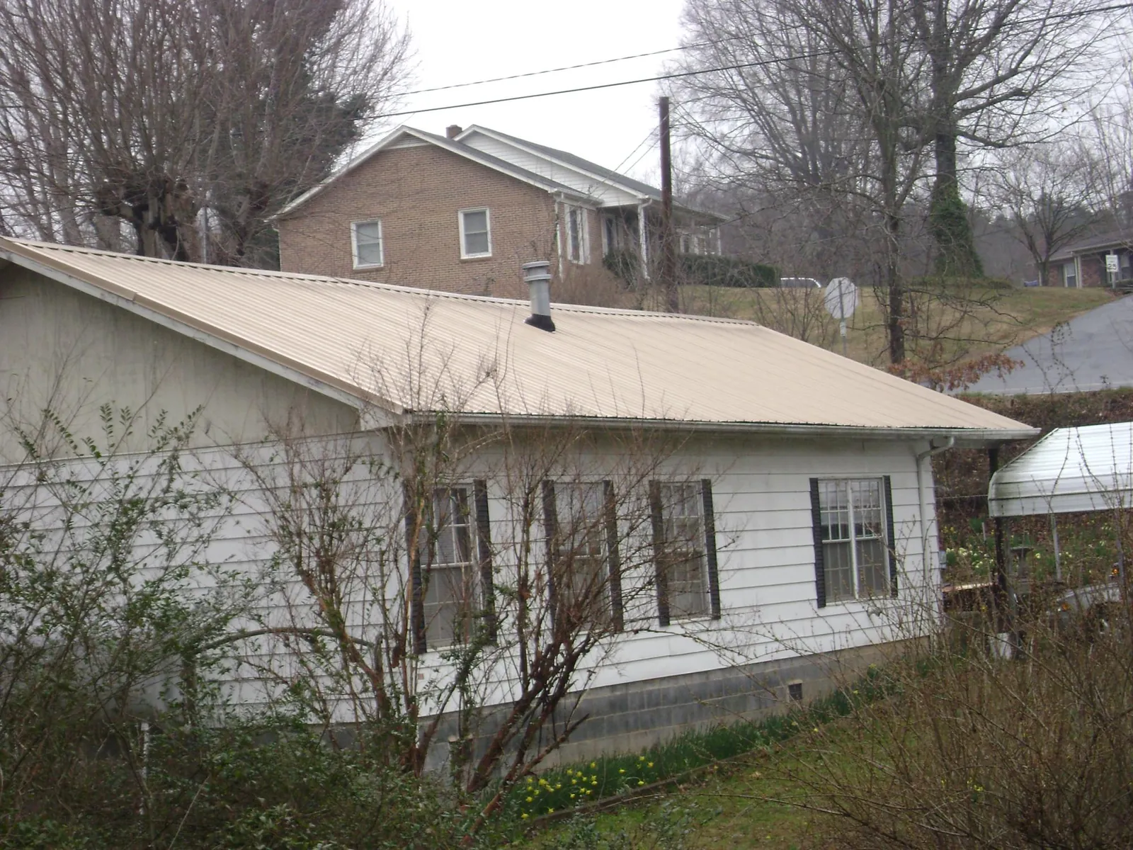 Tan metal roof on a white sided house set into a hillside — Commercial Roofing by Roofing Brothers in Oak Forest