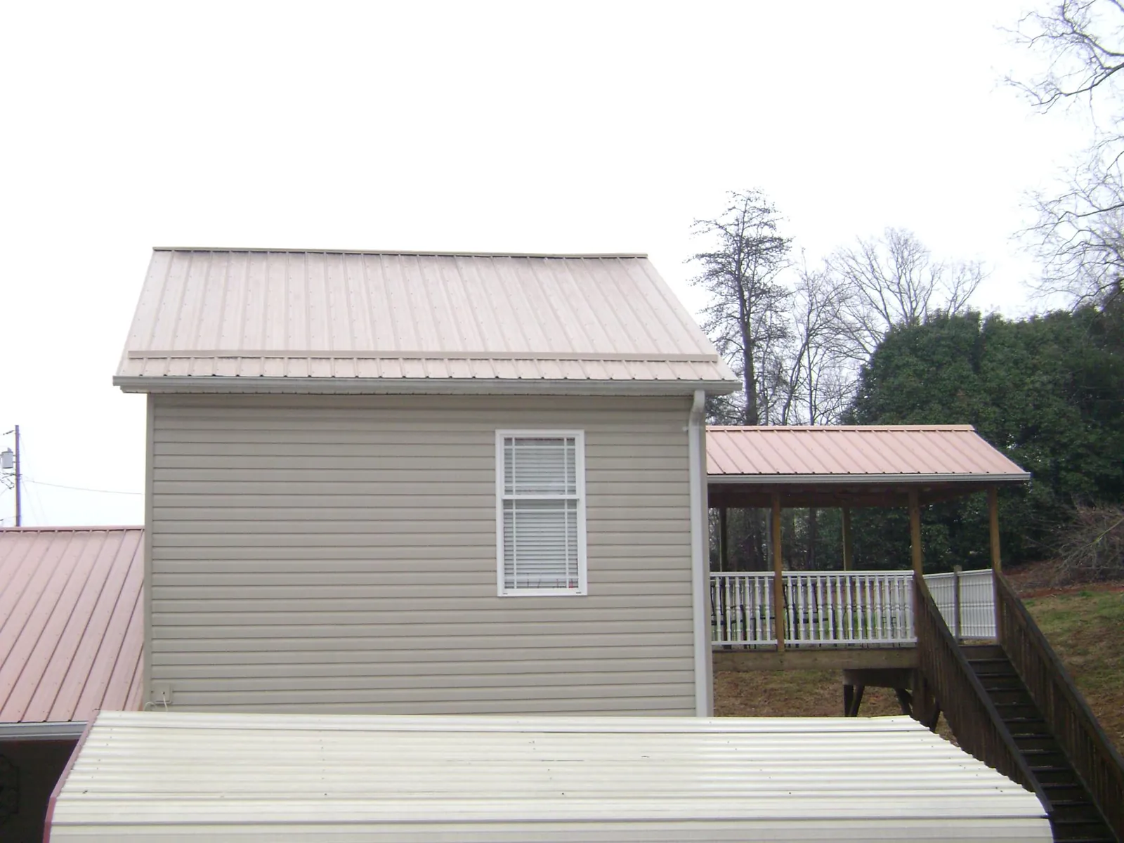 Tan metal roofs on a two story addition and attached porch, from a Roof Replacement job in Oak Forest